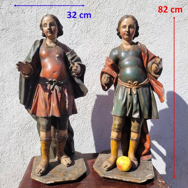 Pair of carved and polychrome wooden sculptures depicting two elegant young figures standing, dressed in short, belted...