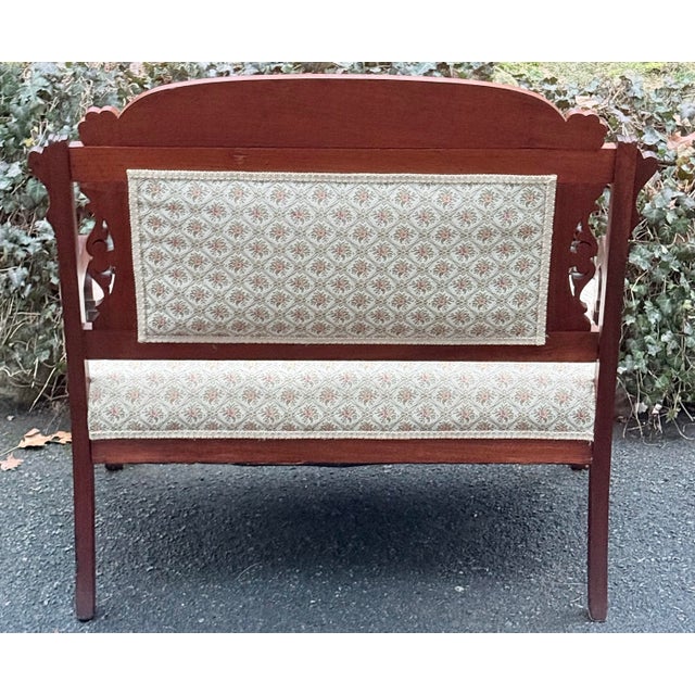 Beautiful settee exhibits characteristics of the Victorian Eastlake style, evident in the geometric and incised carvings...
