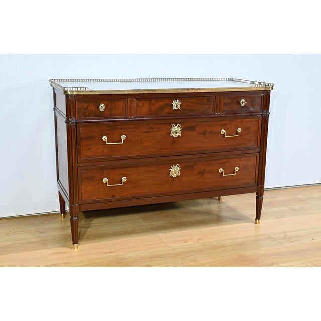 This mahogany chest of drawers opens in a belt with three slightly recessed drawers surrounded by strips with oval...