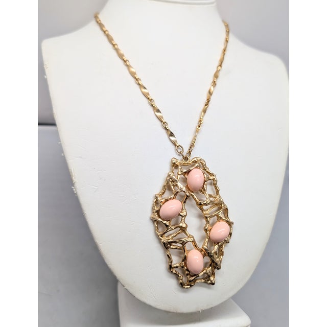 1973 Modernist goldtone openwork with four cabochon faux-coral pendant on a chain with spring ring clasp. Marked "NAPIER©"...