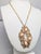 1973 Modernist goldtone openwork with four cabochon faux-coral pendant on a chain with spring ring clasp. Marked "NAPIER©"...