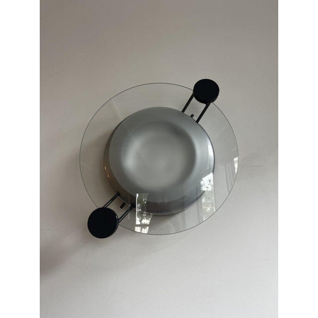 The 'Cyclos' wall lamp from the renowned Italian design brand Artemide. This lamp combines sleek geometric shapes with a...
