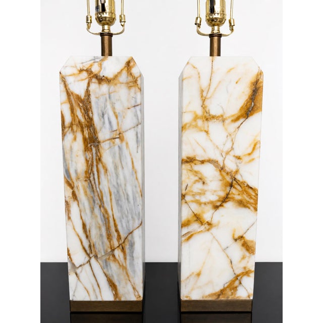 A striking pair of substantial solid marble table lamps, featuring richly expressive amber and honey-toned veining set...