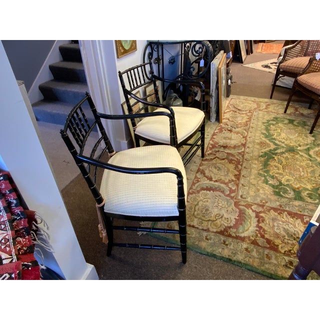 Pair of Regency style faux bamboo armchairs with ebonized finish. Circa 1970. Fixed upustered seat.