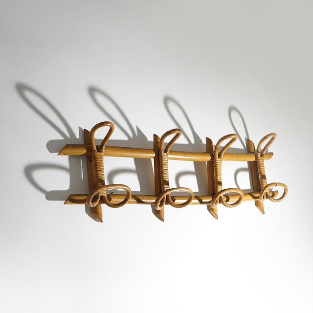 An elegant wall coat rack in rattan and woven wicker, embodying the light and natural aesthetic that defined 1960s design....