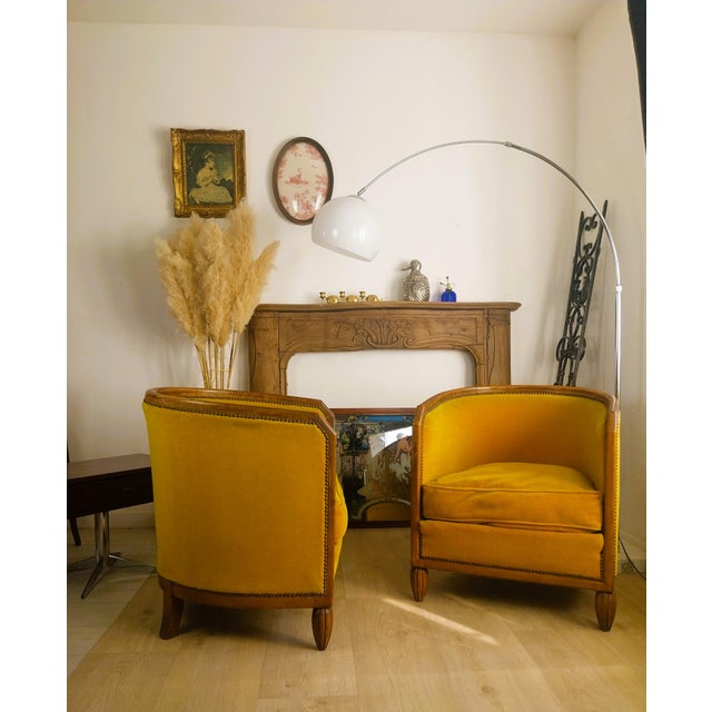 An elegant pair of Art Deco barrel chairs in solid wood, resting on fluted legs. They retain their original upholstery and...