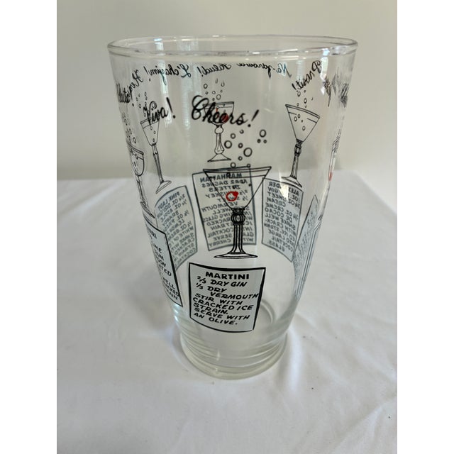Charming clear glass cocktail shaker decorated with black and red cocktail illustrations, six classic drink recipes, and...