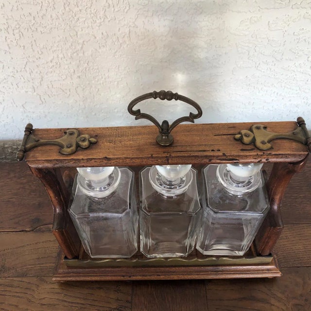A very special three bottle crystal decanter tantalus executed with brass mounts on an oak platform. The latch mechanism...