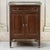 A French Louis XVI mahogany cabinet crowned with Carrara marble and a pierced brass gallery, glowing with the deep, warm...