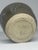 A small handmade studio pottery cup with a rich, variegated dark ash glaze that breaks to lighter tones where it pools and...
