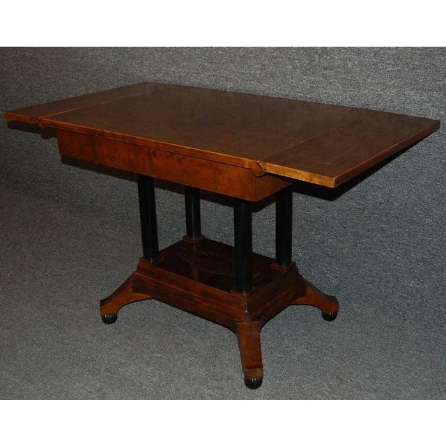 Karl Johan center table of dark flame birch with ebonized four-column pedestal base.