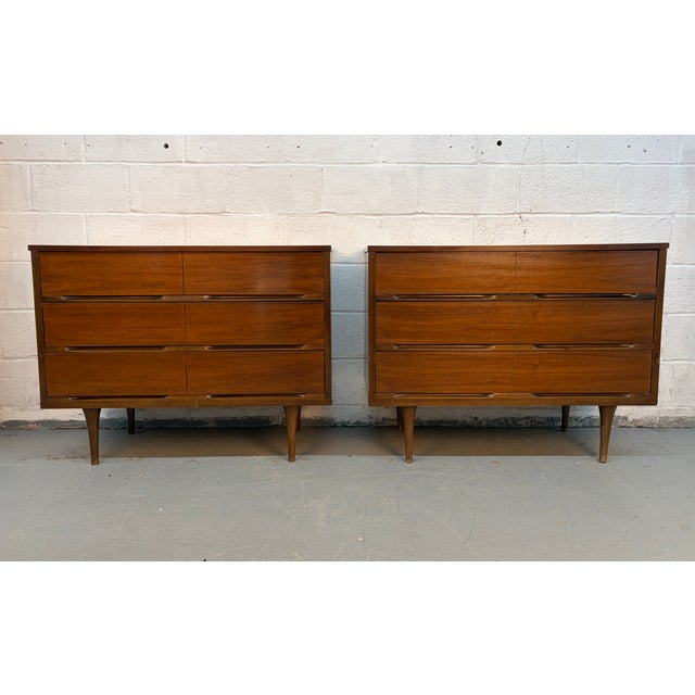 Bring timeless style and functionality to your space with this striking pair of Mid-Century Modern walnut dressers....