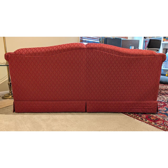 Traditionally styled sofa with rolled arms, patterned woven jacquard fabric upholstery, two-cushion layout, and a warm red...