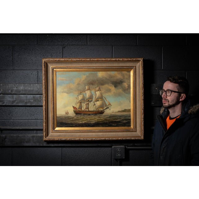 Mid-20th-century oil on canvas depicting a British sailing ship underway on choppy seas beneath a dramatic cloud-filled...