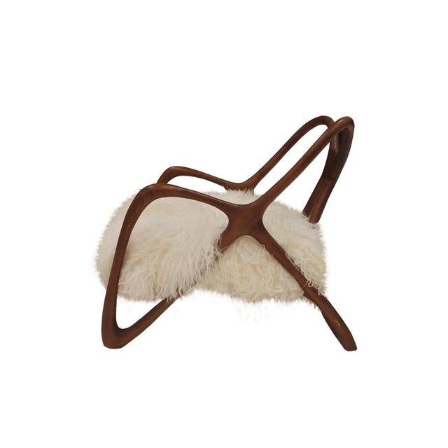 Pair of contemporary armchairs with a sculptural form, inspired by butterfly wings, handcrafted in solid teak wood by...