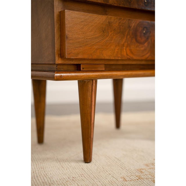 A pair of burl walnut nightstands with two drawers each, featuring expressive burl grain and brass mounts. The clean,...