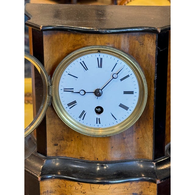 English walnut mantel clock of architectural form with a shaped top and stepped base, the figured walnut case with...