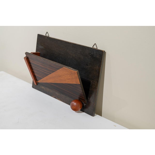 Art Deco style wall-mounted letter or magazine organizer. It features a dark back panel with metal hooks and a front...
