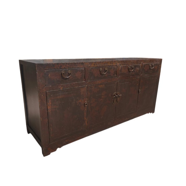 Dating to circa 1926, this antique Chinese sideboard has a rich dark brown finish, beautifully aged patina, and layers of...