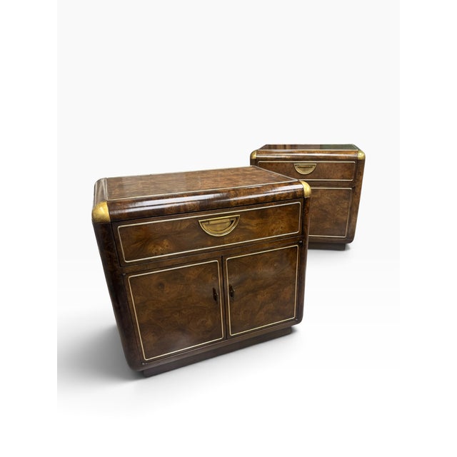 A striking pair of vintage Mastercraft nightstands featuring richly figured burl wood accented with brass detailing and...