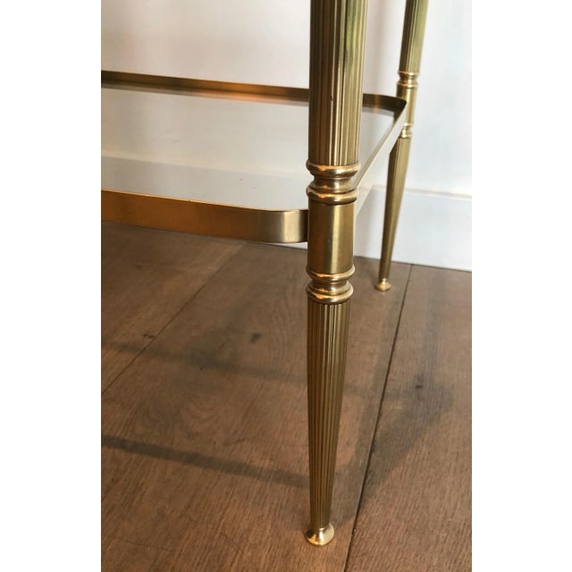 This pair of neoclassical style side tables are made of brass with fluted legs and rounded corners. They have 2 glass...