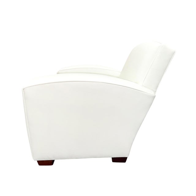Classic club armchair upholstered in crisp white leather, featuring a deep, comfortable seat, softly sculpted arms, and a...