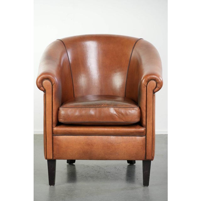 This vintage sheepskin club chair features a warm color scheme and is finished with black piping and a separate seat...