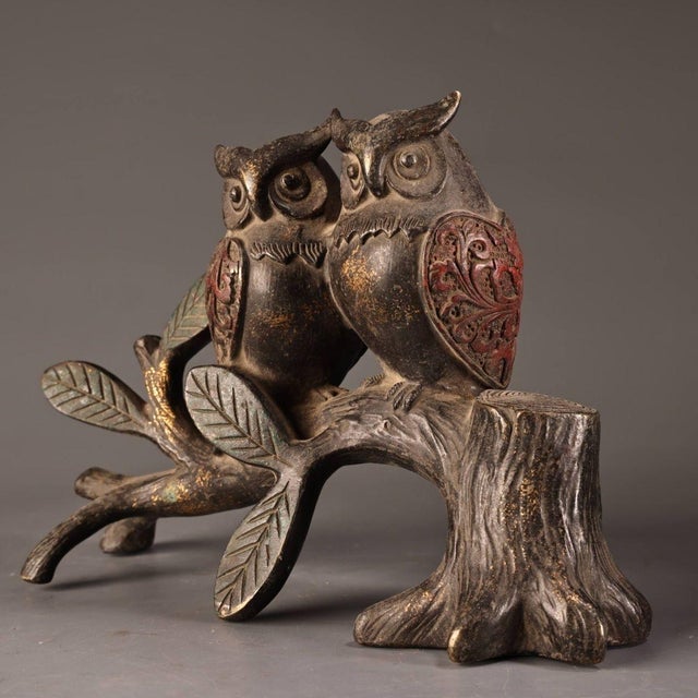 This charming sculpture depicts two owls perched side-by-side on a gnarled tree branch and stump. The piece is crafted...