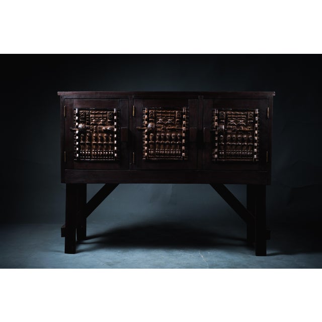 This sculptural console features three intricately carved panels inspired by traditional Dogon doors from Mali. Each...