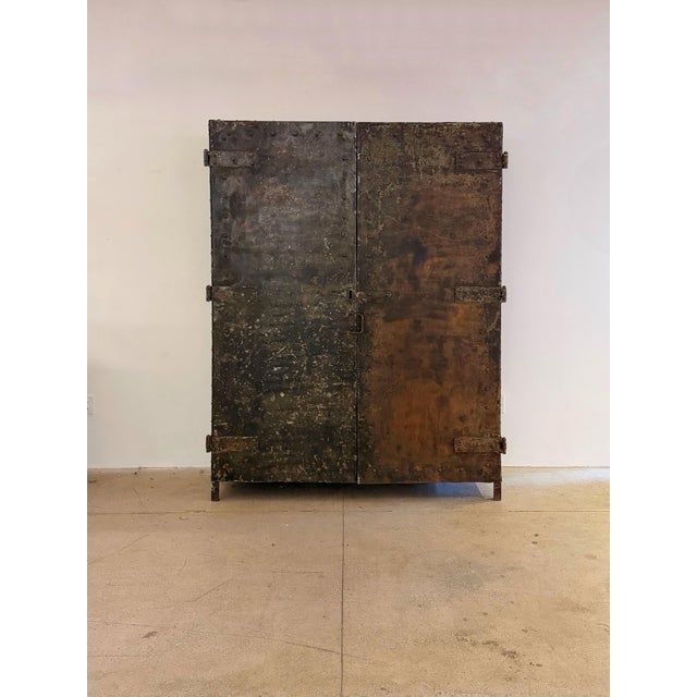 Monumental riveted sheet steel cabinet with hinged doors, integral shelving, and original industrial paint. Constructed...
