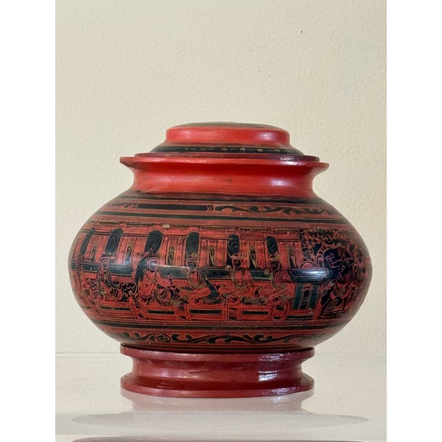 A lacquered jar with separate lid and foot. The fine red lacquer decorated with green and black. Well depicted with people...