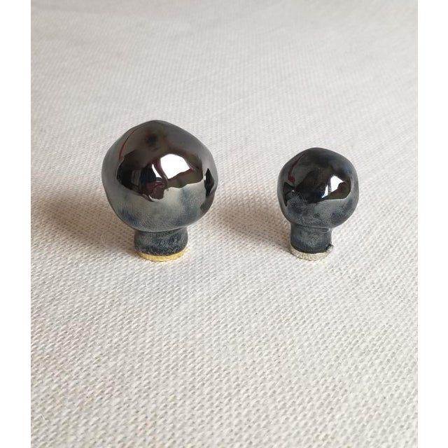 Pair of large modelled, ball shaped lamp shade finials with metallic black glaze. (there is a smaller size available)...