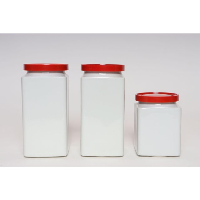Set of three vintage ceramic canisters with red melamine/plastic and rubber lids designed by Richard Lindh for Arabia (ca....