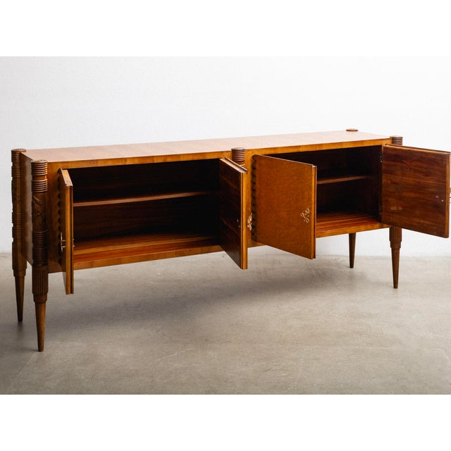 Four-door credenza designed by Pier Luigi Colli. The piece features carved column supports with decorative detailing,...