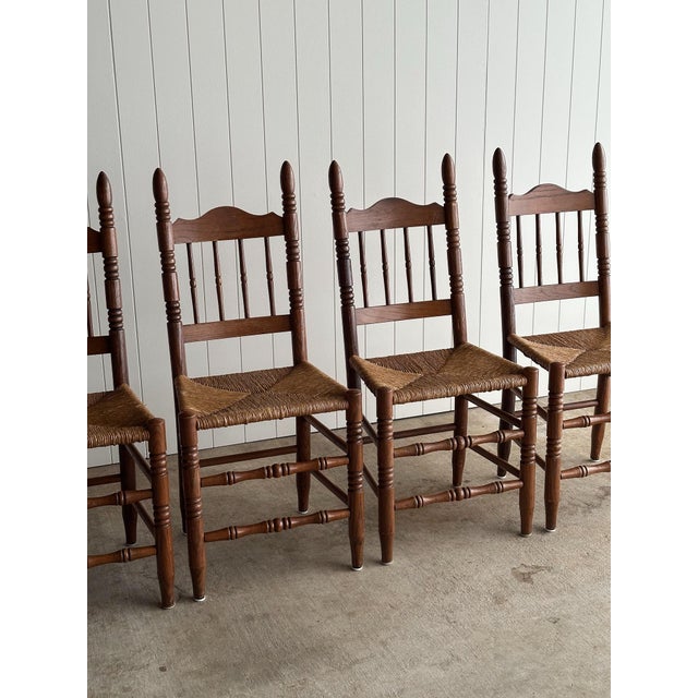 Set of four vintage oak dining chairs with turned posts, spindle backs, and hand-woven rush seats. Light surface wear...