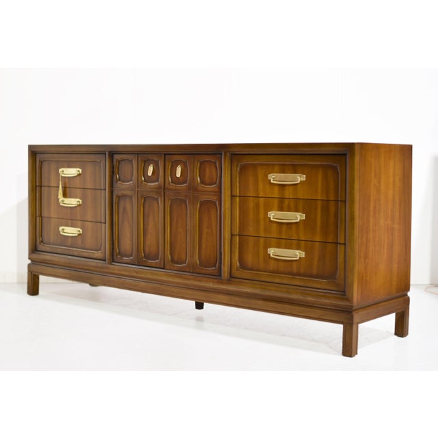 A low, long, and quietly commanding presence — this 1970s Campaign style lowboy dresser by Henry M. Goodman Furniture is...