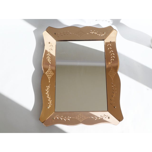 A rectangular vintage Venetian mirror with etched glass. The frame of the mirror is pink/copper in colour and has...
