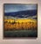 The artwork depicts a vibrant landscape where golden autumn foliage contrasts with the dark, moody mountains in the...