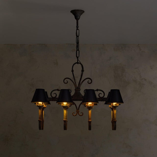 A French hand-forged wrought iron chandelier from the 1940s. Suspended from an iron chain, the chandelier unfolds outward...
