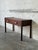 This minimalist hallway console table features a long rectilinear top flanked by slightly raised side lip borders. Two...