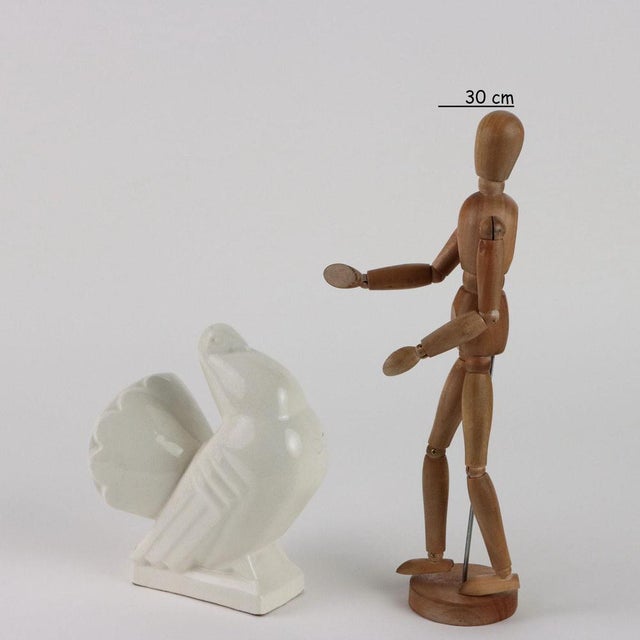 Ceramic deco sculpture depicting a pigeon. Manufacturer's mark printed inside. This piece is attributed to the mentioned...
