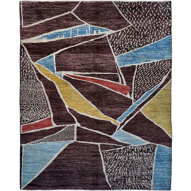 Intersecting ivory lines divide this handmade wool rug into irregular geometric shapes. Deep burgundy and plum-brown...