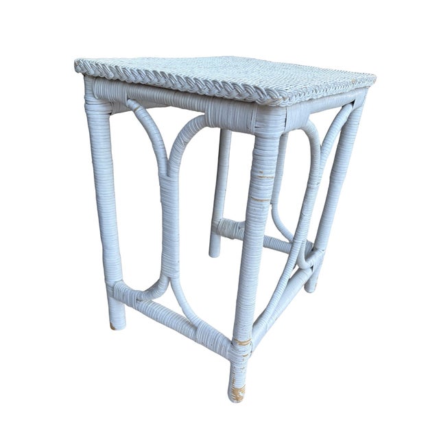 This piece is a charming vintage white wicker side table with beautifully aged character. It features a woven top with a...