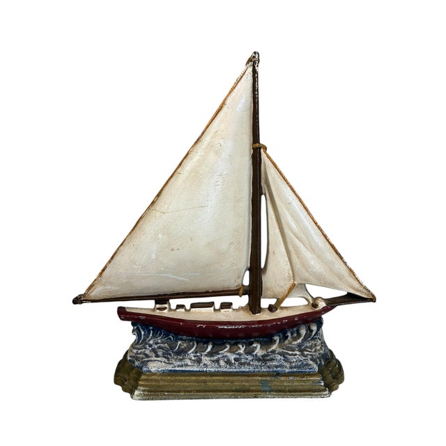 A vintage cast iron sailboat doorstop — a wonderfully heavy, hand-painted piece of American nautical folk art. Full pale...