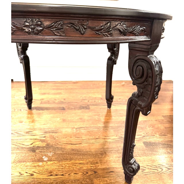 Elegant vintage dining table featuring hand-carved scroll and foliate detailing along the apron and legs. The table...