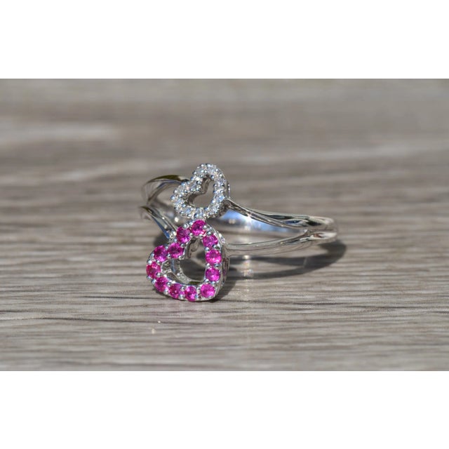 The Thalia Ladies Contemporary Double Heart Ring set with Rubies and Diamonds. Crafted in 14 karat white gold, this ladies...