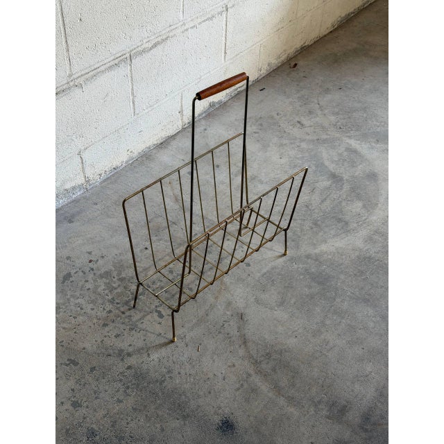 Beautiful vintage Danish magazine rack crafted in brass-tone metal with a teak handle. This elegant Scandinavian modern...
