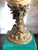 Porcelain nautilus shell form mounted as an open cup on a cast brass pedestal with dolphin figure supporting a foliate...