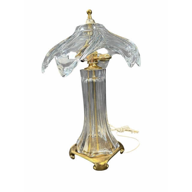 A striking vintage crystal table lamp featuring a sculptural clear crystal body paired with elegant brass-tone accents....