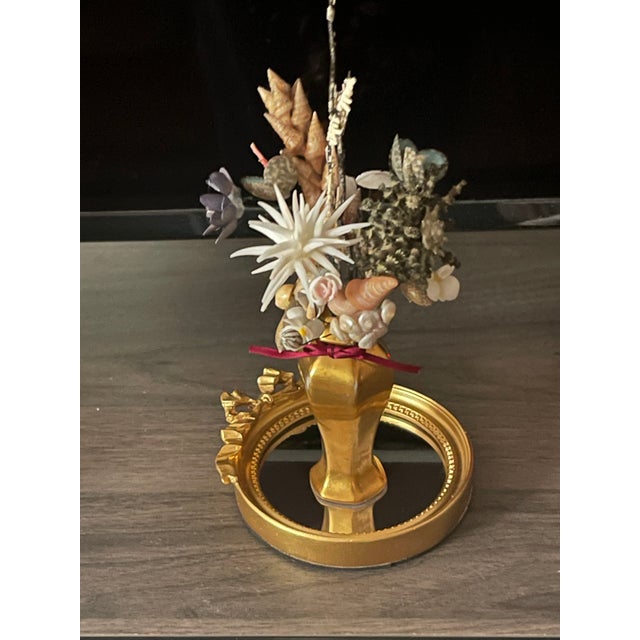 Artisan made by Elia small sea Shell art floral arrangement in gold porcelain stand on a small ormolu mirrored round tray.